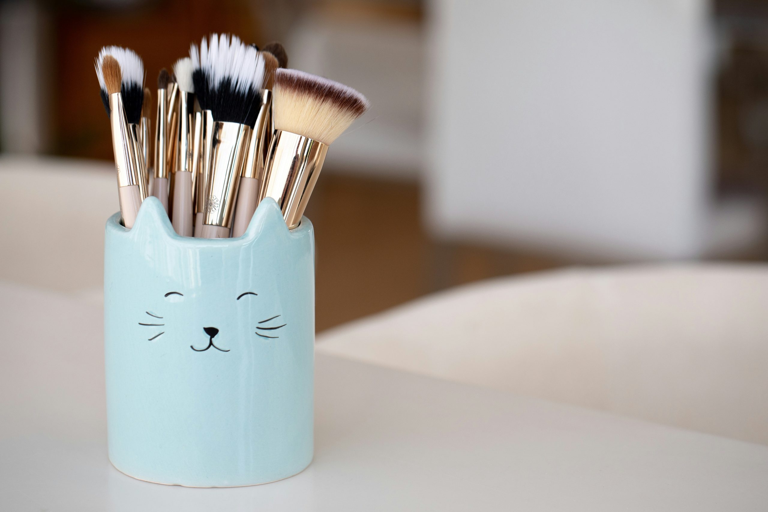 Three brushes next to jars of natural makeup
