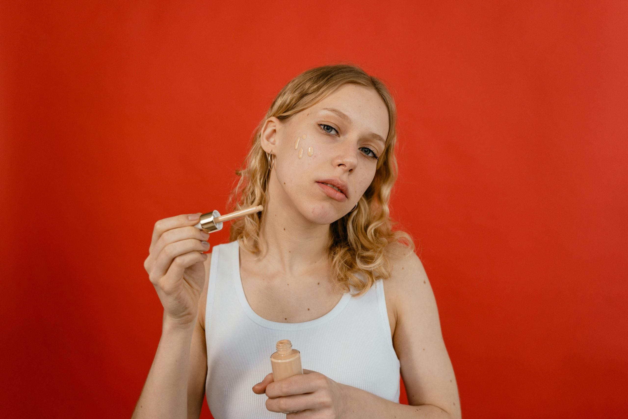 Woman prepping her face for makeup by applying serum and sunscreen