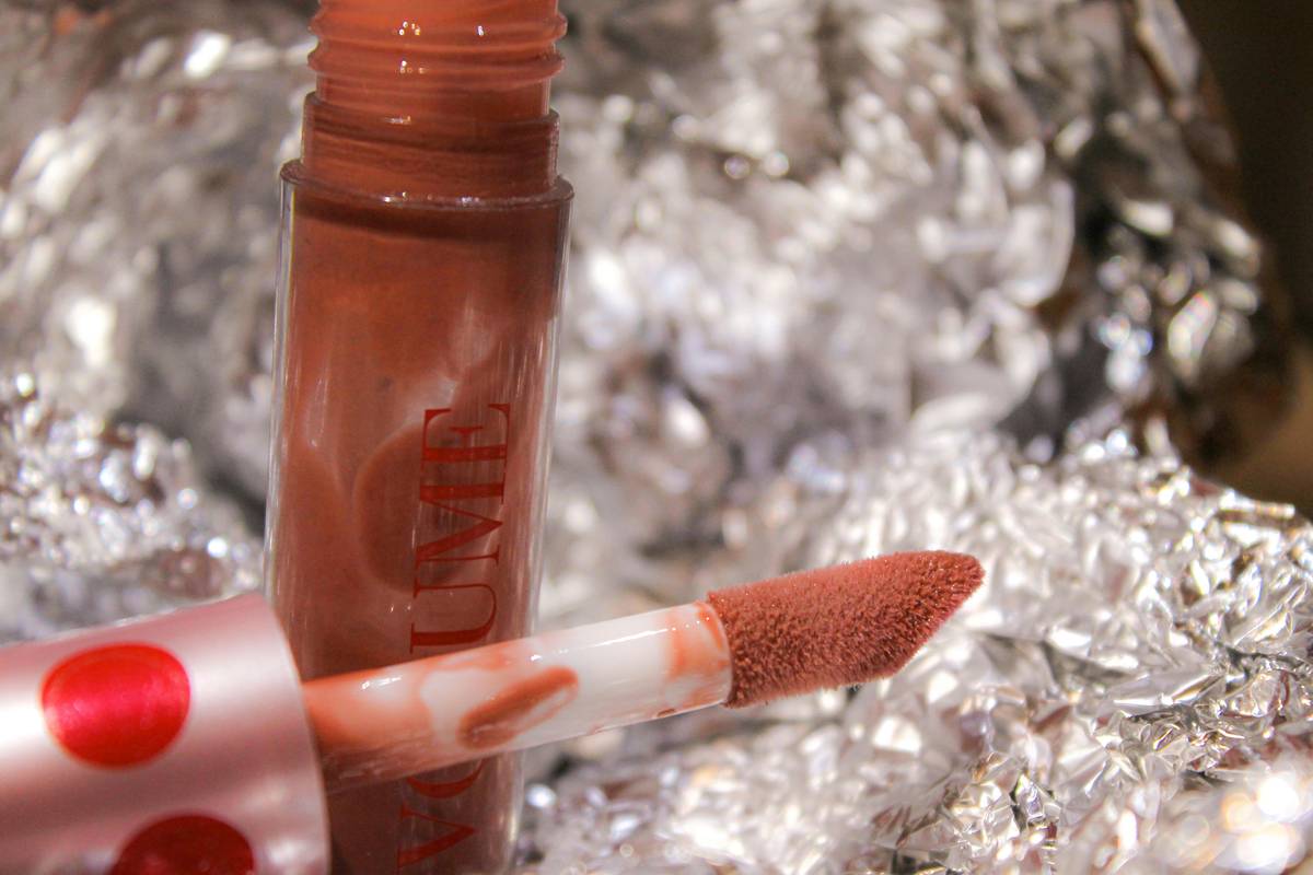 A hand holding three lipsticks against different skin tones