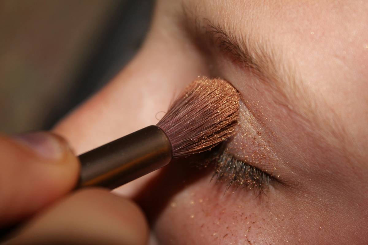 A makeup artist applying green makeup on a model